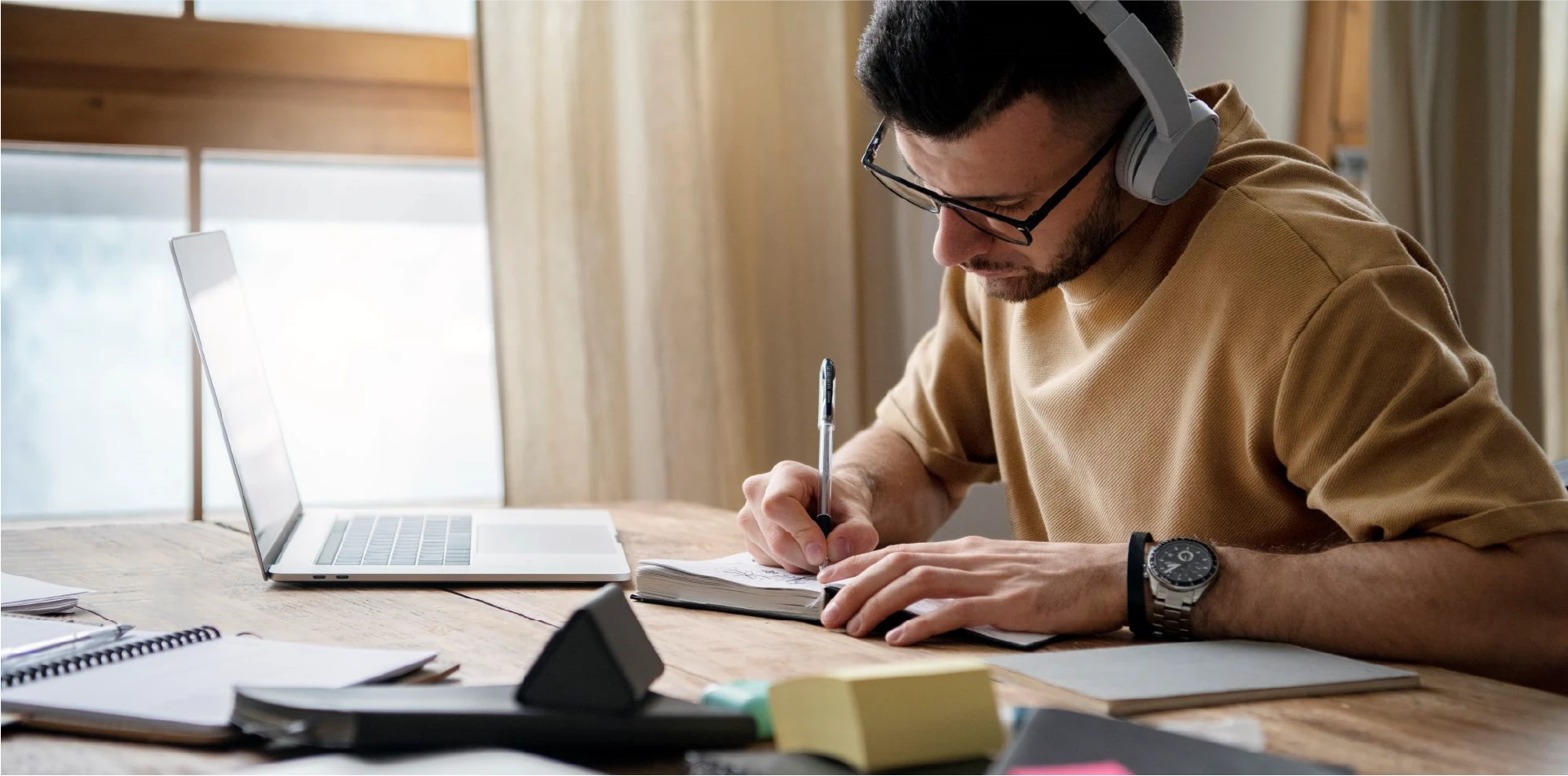A student wearing headphones and taking notes